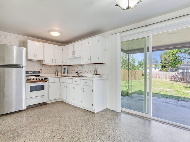 kitchen featuring sink, white range, white cabinetry, and stainless steel refrigerator