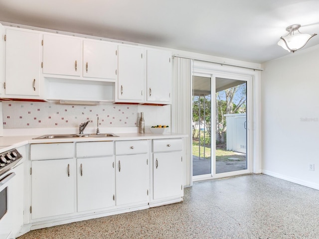 kitchen with sink, white gas stove, white cabinets, and tasteful backsplash