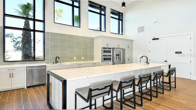 kitchen featuring a kitchen island, a kitchen bar, a high ceiling, and appliances with stainless steel finishes