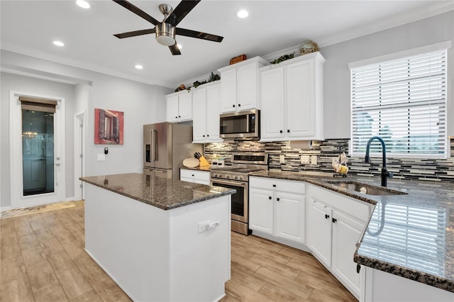 kitchen with a kitchen island, appliances with stainless steel finishes, white cabinetry, sink, and dark stone countertops