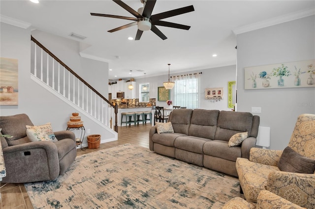 living room with crown molding, ceiling fan, and light hardwood / wood-style floors