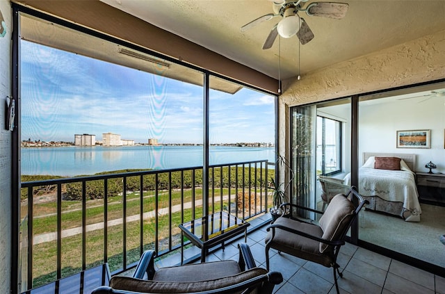 sunroom / solarium with a water view and ceiling fan