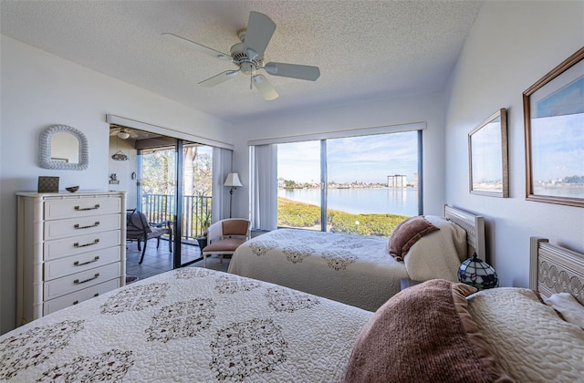 bedroom featuring a water view, ceiling fan, access to exterior, and a textured ceiling