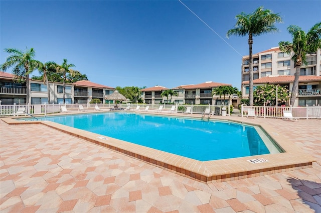 community pool with a patio and fence