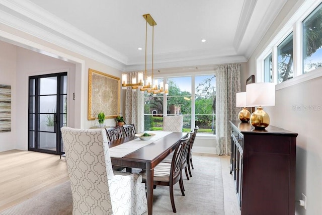 dining space with crown molding, a chandelier, and light hardwood / wood-style flooring