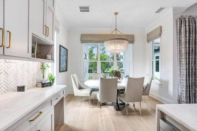 dining area with crown molding, a notable chandelier, and light wood-type flooring