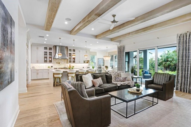 living room featuring ceiling fan, beam ceiling, and light wood-type flooring