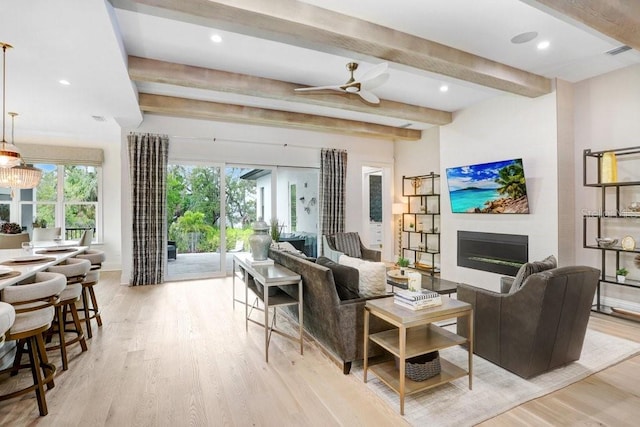 living room featuring beam ceiling, ceiling fan with notable chandelier, and light hardwood / wood-style floors