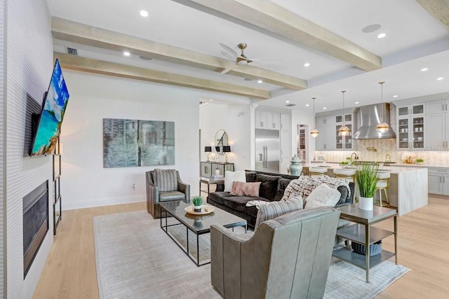 living room featuring beamed ceiling, ceiling fan, and light hardwood / wood-style floors