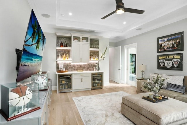 bar featuring white cabinets, wine cooler, backsplash, and a tray ceiling