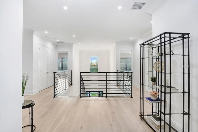 corridor with ornamental molding and light hardwood / wood-style flooring