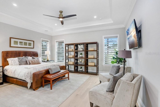 bedroom featuring a raised ceiling, ornamental molding, ceiling fan, and light hardwood / wood-style floors