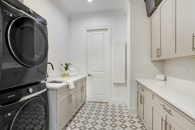 laundry area featuring cabinets, stacked washing maching and dryer, sink, and crown molding