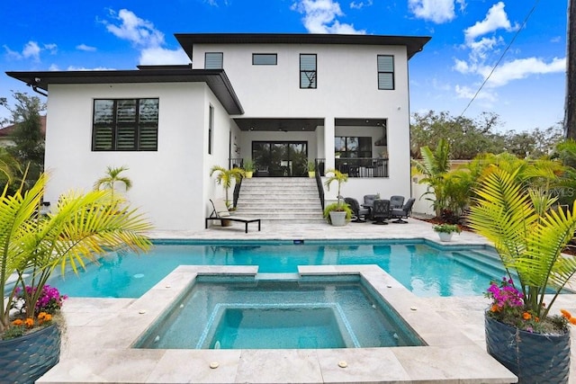 back of house featuring a swimming pool with hot tub and a patio area