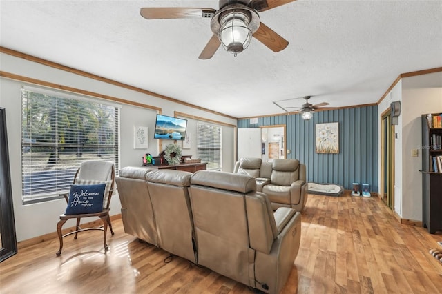 living room with ceiling fan, crown molding, a textured ceiling, and light wood-type flooring