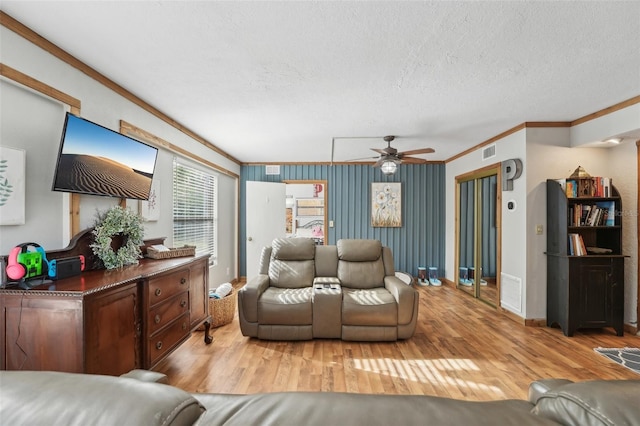 living room with ornamental molding, ceiling fan, a textured ceiling, and light hardwood / wood-style floors