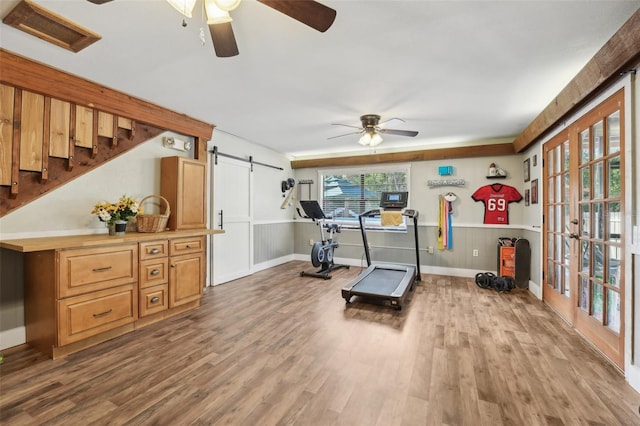 workout area with hardwood / wood-style flooring, a barn door, ceiling fan, and french doors