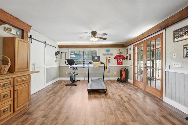 exercise room featuring french doors, ceiling fan, a barn door, and hardwood / wood-style flooring