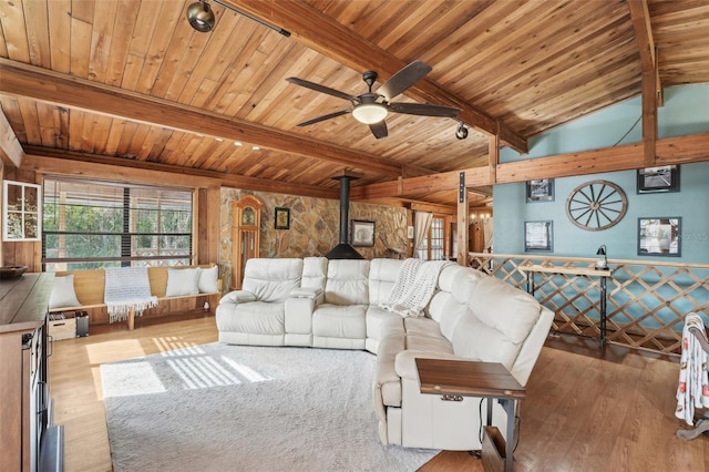 living room featuring wood ceiling, a wood stove, ceiling fan, vaulted ceiling with beams, and light wood-type flooring