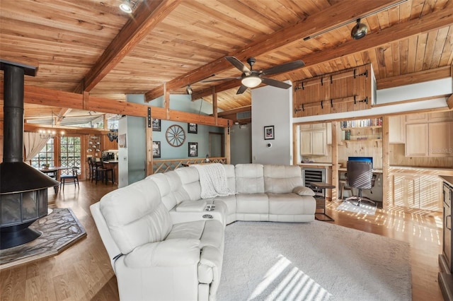 living room featuring ceiling fan, vaulted ceiling with beams, wood-type flooring, wooden ceiling, and a wood stove