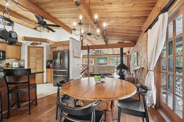 dining room featuring lofted ceiling with beams, a wood stove, wooden ceiling, and light hardwood / wood-style floors