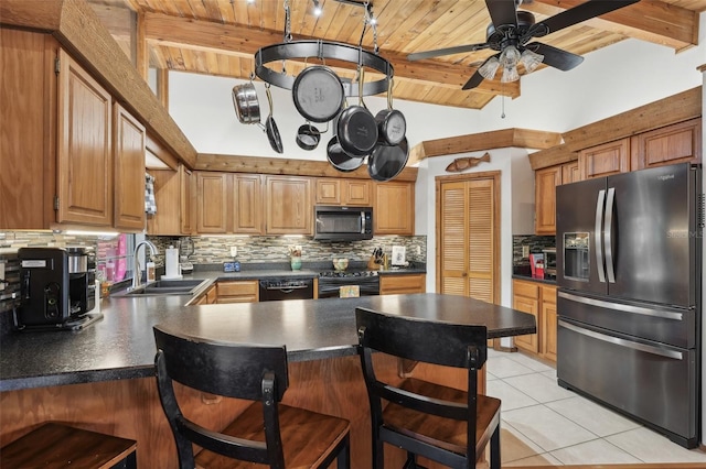 kitchen with sink, light tile patterned floors, a breakfast bar area, black appliances, and kitchen peninsula