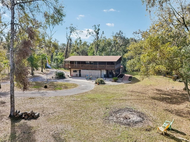 front facade with a garage, a front yard, and a deck