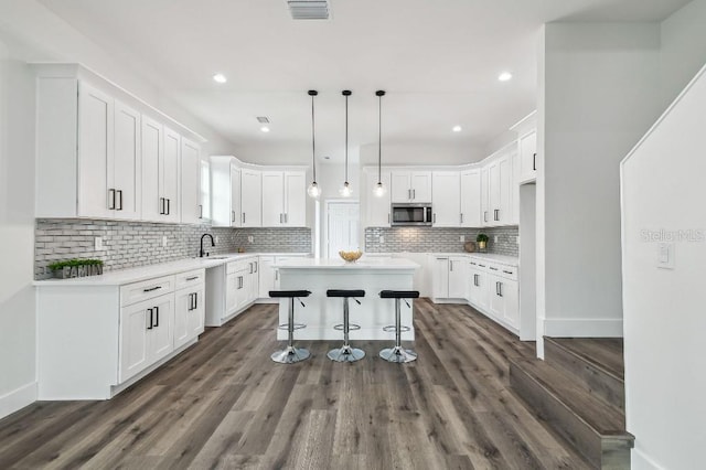 kitchen with white cabinetry, a center island, sink, and hanging light fixtures