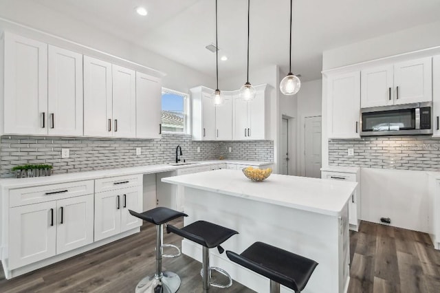 kitchen featuring white cabinetry, decorative light fixtures, a kitchen island, and backsplash