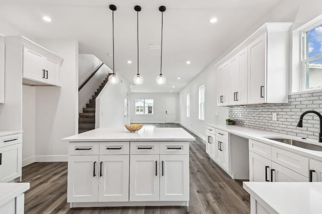 kitchen with hanging light fixtures, white cabinetry, sink, and backsplash