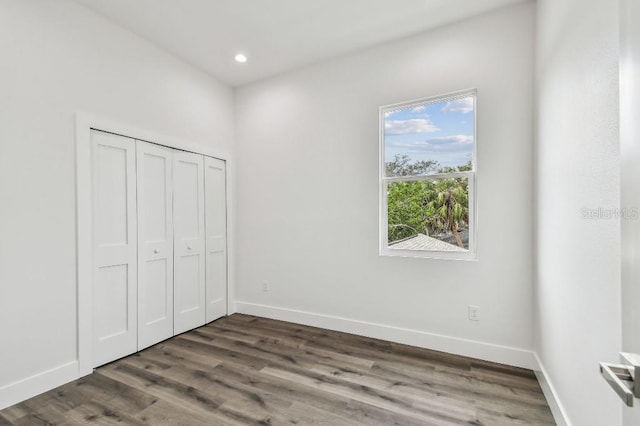 unfurnished bedroom with dark hardwood / wood-style flooring and a closet