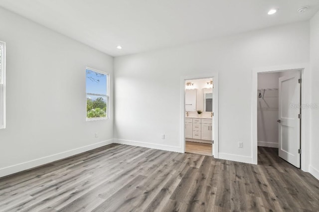 unfurnished bedroom featuring hardwood / wood-style floors, a walk in closet, a closet, and ensuite bathroom