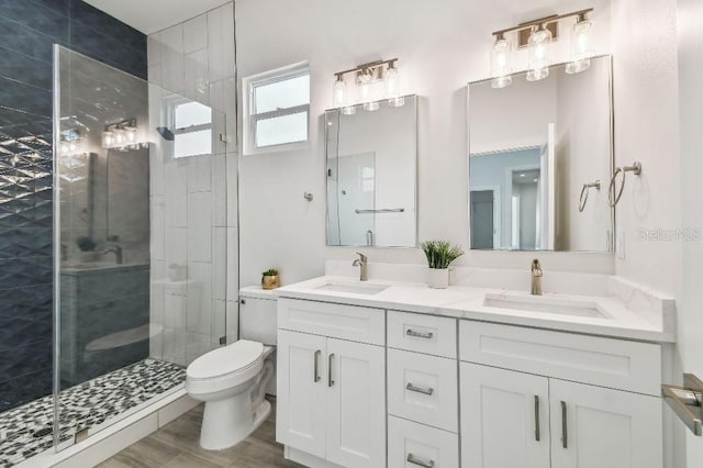 bathroom featuring toilet, hardwood / wood-style floors, vanity, and a shower with shower door