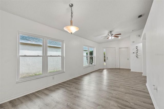 unfurnished room featuring hardwood / wood-style flooring, lofted ceiling, and a textured ceiling