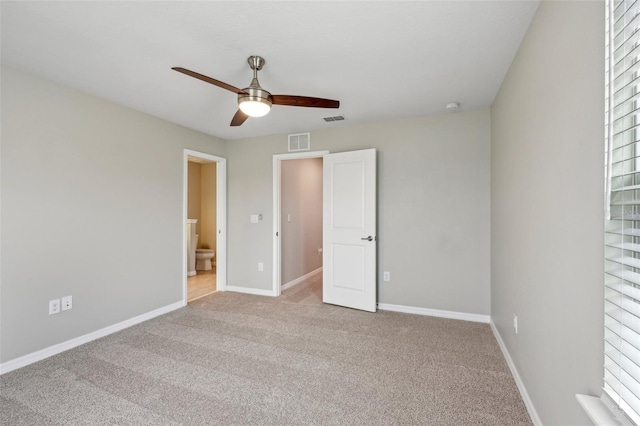 unfurnished bedroom featuring ceiling fan, ensuite bathroom, and light colored carpet