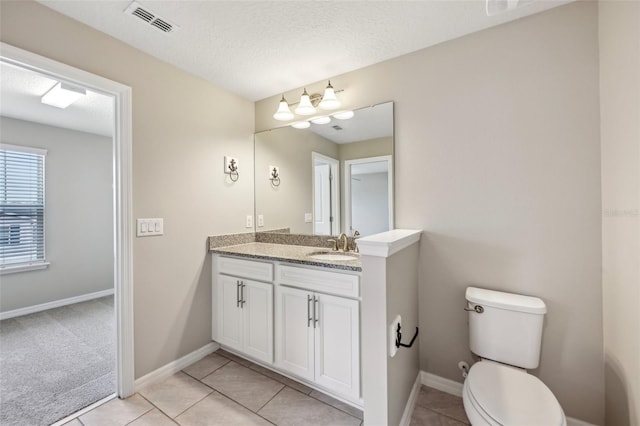 bathroom with tile patterned floors, toilet, a textured ceiling, and vanity