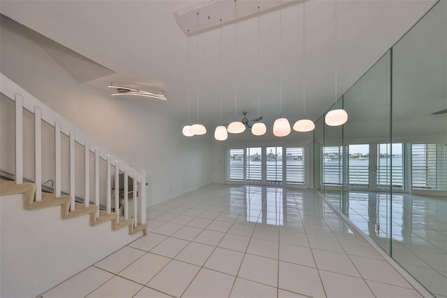 empty room with a towering ceiling, tile patterned floors, and a water view