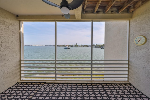 unfurnished sunroom featuring ceiling fan, a water view, and a healthy amount of sunlight