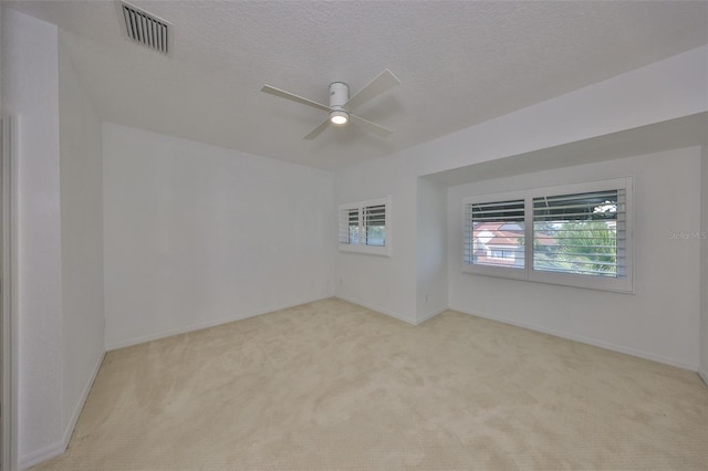 carpeted spare room with a textured ceiling and ceiling fan