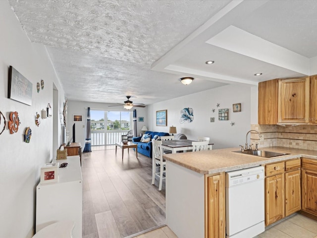 kitchen featuring sink, backsplash, white dishwasher, and kitchen peninsula