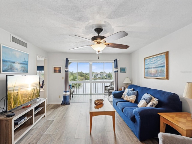 living room featuring a textured ceiling, light hardwood / wood-style floors, and ceiling fan