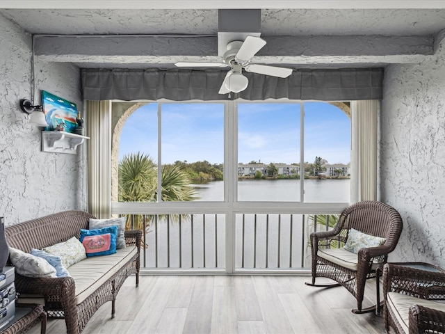 sunroom featuring ceiling fan and a water view