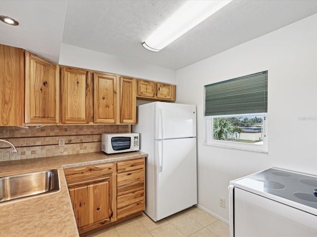 kitchen with sink, white appliances, a textured ceiling, light tile patterned flooring, and decorative backsplash