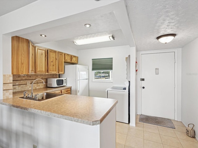 kitchen featuring sink, white appliances, tasteful backsplash, washer / dryer, and kitchen peninsula