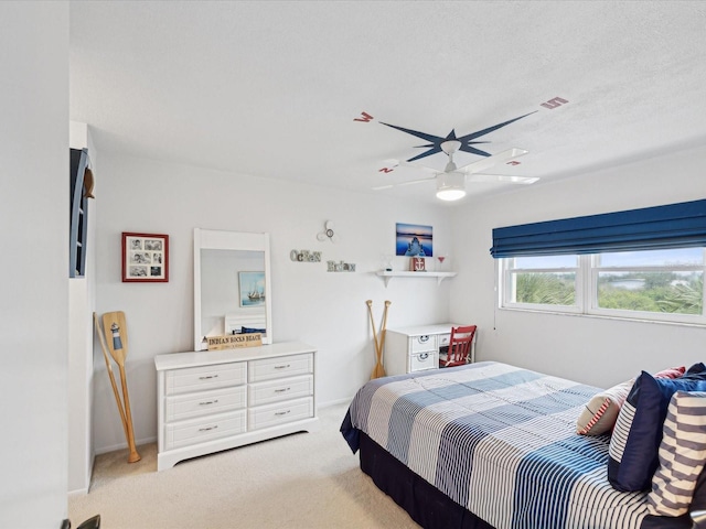 bedroom featuring ceiling fan, light carpet, and a textured ceiling