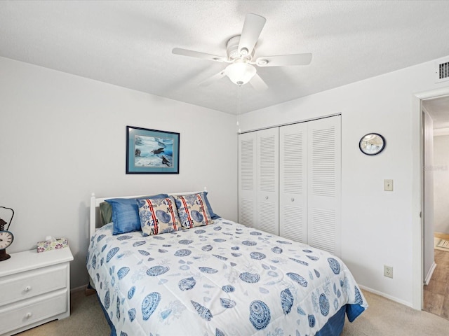 carpeted bedroom featuring a textured ceiling, ceiling fan, and a closet