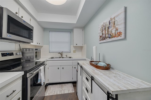 kitchen featuring sink, white cabinets, dark hardwood / wood-style flooring, backsplash, and stainless steel appliances