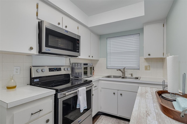 kitchen with sink, white cabinetry, decorative backsplash, and appliances with stainless steel finishes