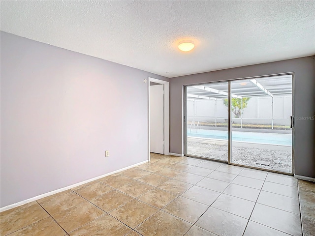 empty room with light tile patterned floors and a textured ceiling