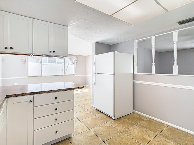 kitchen featuring white cabinetry, a textured ceiling, white fridge, and light tile patterned floors